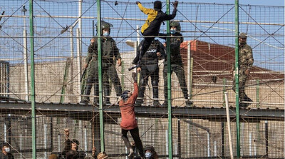 Des migrants escaladent la clôture qui sépare le Maroc de Melilla, le 24 février 2022. Crédit : Javier Bernardo/AP/picture-alliance