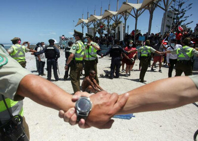 Des membres de la police chilienne forment un périmètre autour d’un migrant vénézuélien lors d’un rassemblement contre la migration et la délinquance, à Iquique, au Chili, le 30 janvier 2022. STRINGER / REUTERS