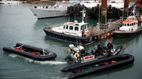 Des membres de la police des frontières transportent des embarcations utilisées par des migrants dans le port de Douvres, au Royaume-Uni, le 14 avril 2022. Crédit : Reuters