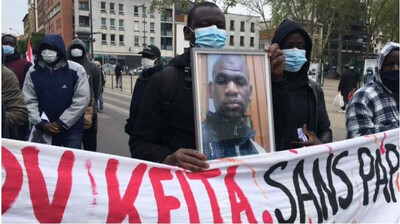 Boubou Konaté tient une photo de son cousin Bary Keita, victime d'un accident du travail, lors de l'hommage qui lui a été rendu, le 1er mai, à Montreuil. Crédit : InfoMigrants
